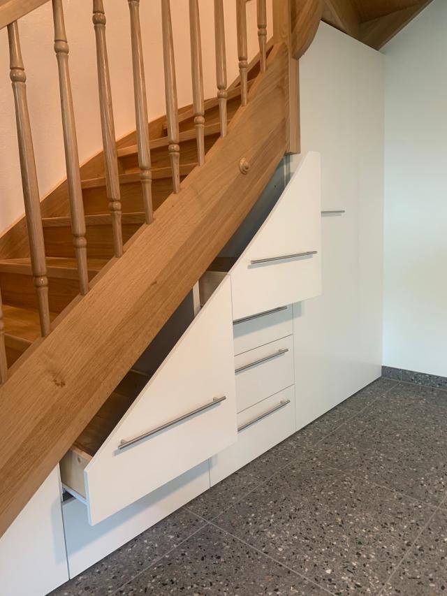 Eingepasster Schrank unter der Treppe, Schräge von den Treppenwangen übernommen. Grosse Auszüge und begehbarer Teil für bestmögliche Platzausnützung.