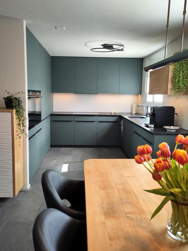 Küche in Steingrün mit Hängemöbel und Tisch in Erle