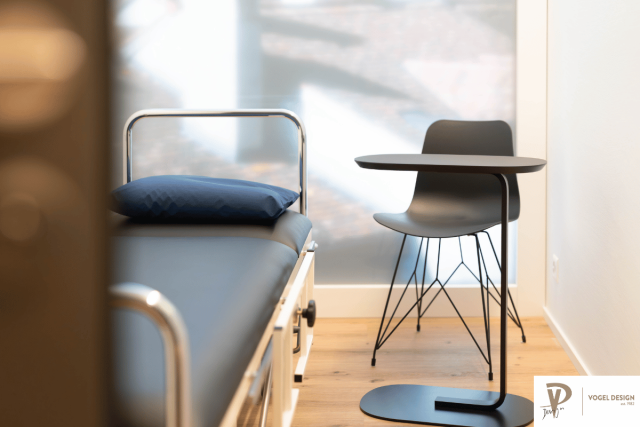 Helles Behandlungszimmer mit Bett und kleinem Tisch